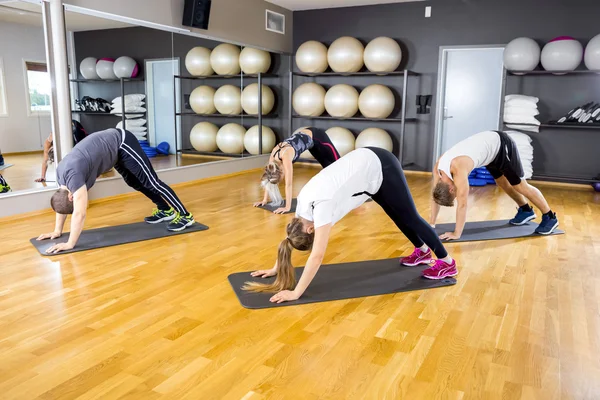 Grupo exercitando flexibilidade corporal e equilíbrio na academia de fitness — Fotografia de Stock
