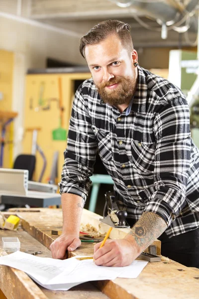 Glimlachend timmerman planning werk in de werkplaats — Stockfoto