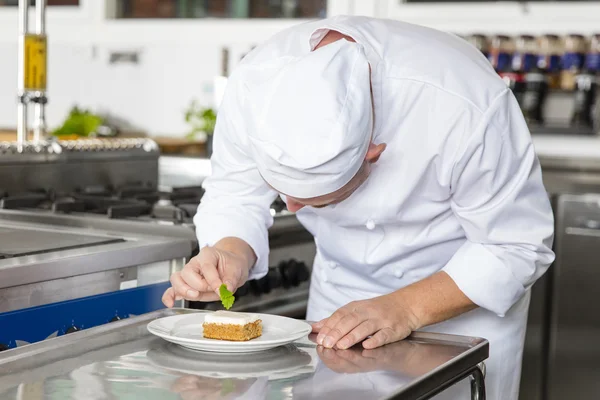 Профессиональный повар украшает десертный торт лимонным листом — стоковое фото