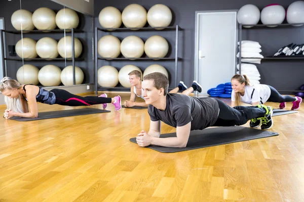 Skupina lidí, kteří dělají prkno na fitness tělocvičně třída — Stock fotografie