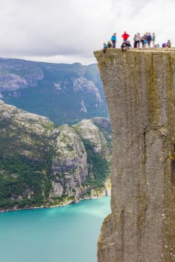 Tourists hiking at the Preikestolen cliff in lysefjorden Norway clipart