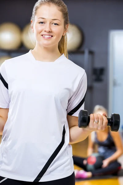 Donna sorridente in abito allenamento tiene manubri in palestra fitness — Foto Stock