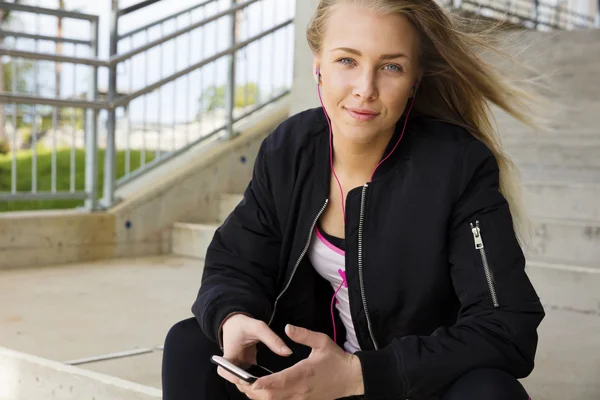 Mujer rubia sonriente se sienta al aire libre y utiliza el teléfono —  Fotos de Stock