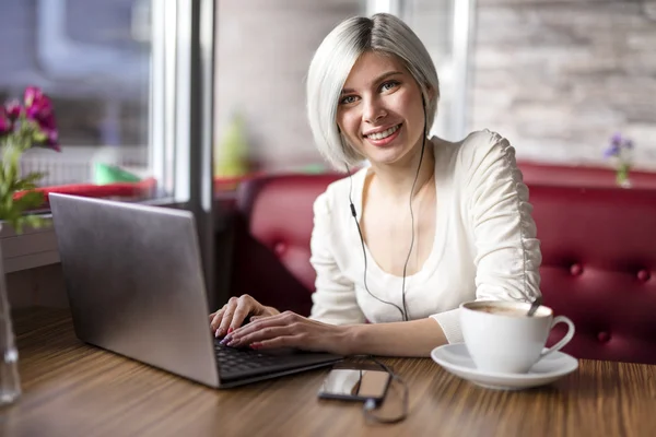 Gladlynt kvinna som arbetar med bärbar dator i café — Stockfoto