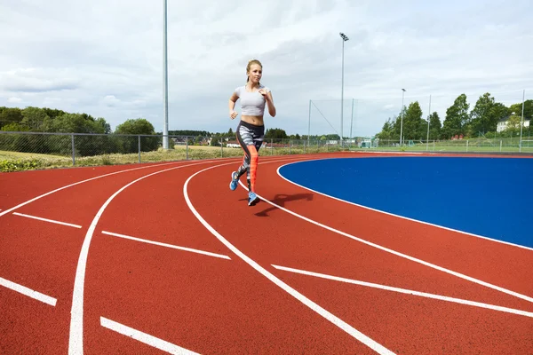 Решительная женщина бежит по спортивным дорожкам — стоковое фото