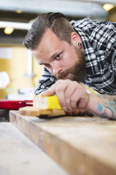 Carpintero lijando un cuello de guitarra en madera en el taller — Foto de Stock