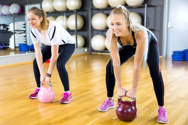 Крупный план тренировок двух женщин с гирями в спортзале — стоковое фото