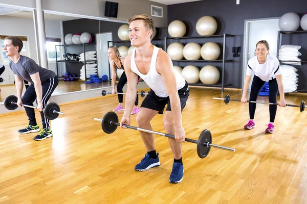 Equipo enfocado haciendo ejercicios de levantamiento de pesas con pesas en gimnasio de fitness — Foto de Stock
