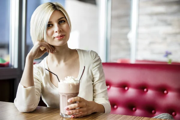 Hermosa mujer teniendo chocolate caliente con crema en el café — Foto de Stock