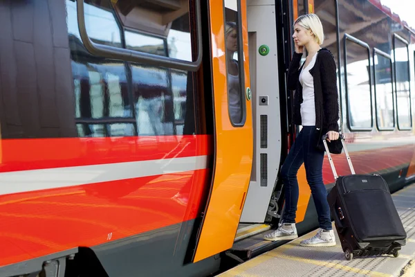 Ung kvinna med hjulförsett bagage ombordstigning tåg — Stockfoto