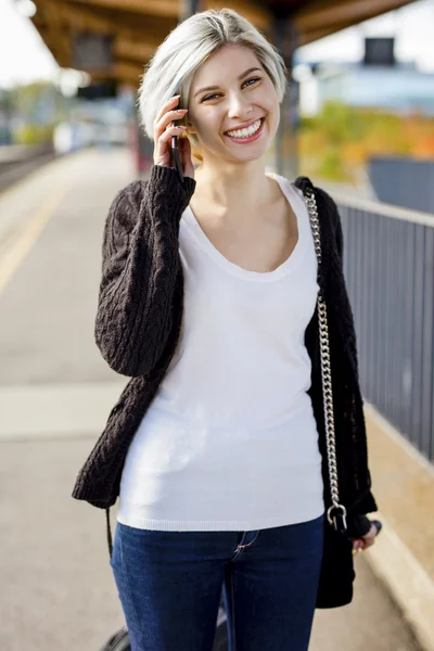 鉄道プラットフォームで携帯電話で話している幸せな女 — ストック写真