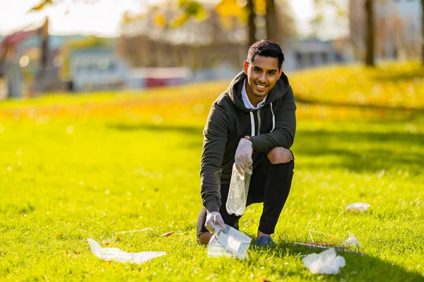 Smiling and committed volunteer cleaning garbage on grass in nature — Stock Photo, Image