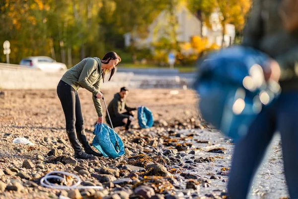 Toegewijd team van vrijwilligers schoonmaken strand op zonnige dag — Stockfoto