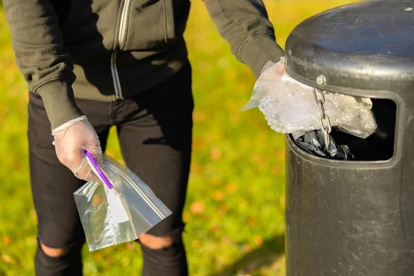 Voluntario poniendo basura plástica en cubo de basura en el parque —  Fotos de Stock