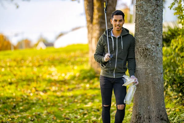 Environmental protection volunteer holding garbage and mechanical grabber — Stock Photo, Image