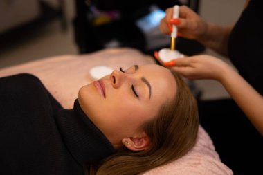 Klinikte, bir güzellik salonundaki bir müşteriye kirpik eklentisi ustası tarafından uygulandı.