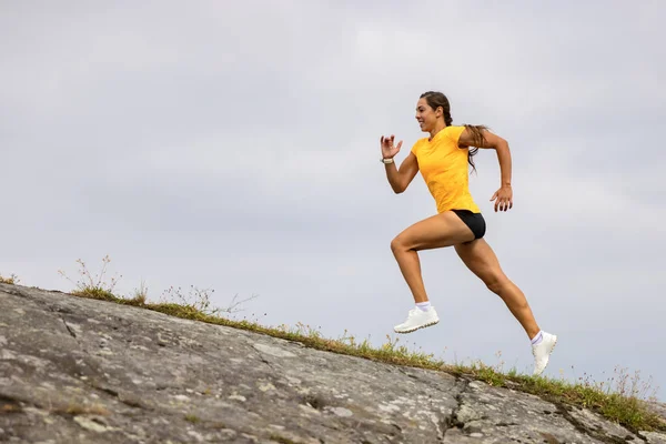 Seitenansicht der Fitness-Frau beim intensiven Laufen am Berghang am Meer — Stockfoto