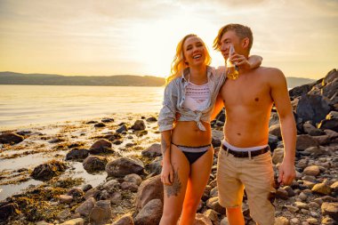 Mutlu çift sahilde eğleniyor ve bira içiyor.