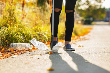 Erkek gönüllü çimlerden plastik topluyor.