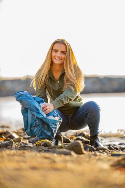 Молодая женщина-волонтер забирает аэрозоль и мусор на пляже — стоковое фото