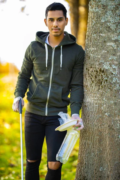 Environmental protection volunteer holding garbage and mechanical grabber — Stock Photo, Image