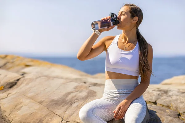 Sportlerin trinkt Wasser beim Outdoor-Training am Meer — Stockfoto