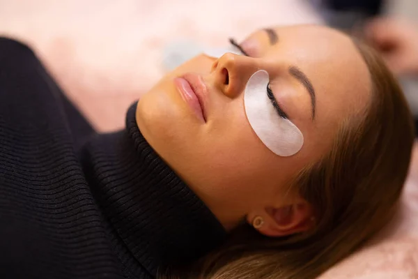 Mujer con almohadillas de algodón acostado durante el tratamiento de extensión de pestañas — Foto de Stock