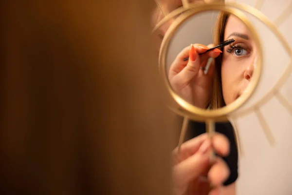 Vrouw houden spiegel terwijl vrouwelijke cosmetica met behulp van Mascara — Stockfoto