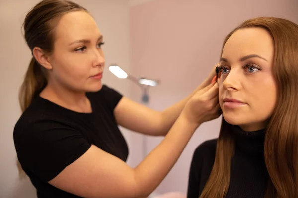 Especialista femenina que usa máscara en las pestañas falsas de los clientes — Foto de Stock