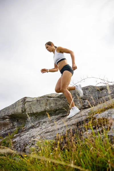 Vista lateral de la mujer fitness haciendo carreras de alta intensidad en la ladera de la montaña —  Fotos de Stock