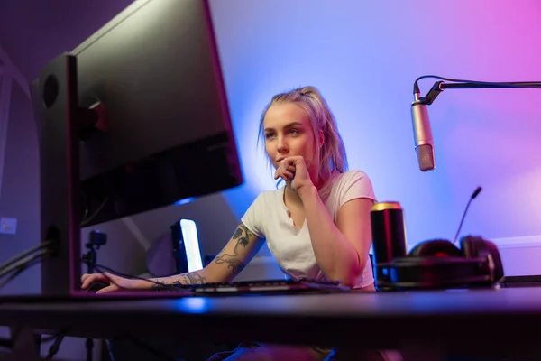 Cool looking professional gamer girl streams and play online multiplayer video game on PC — Stok Foto