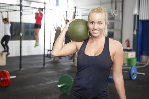 Smiling blonde woman with slam ball at fitness gym — Stock Photo, Image