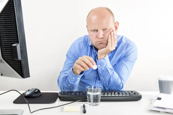 Trabajador de oficina sobrecargado tomando pastillas para el dolor de cabeza — Foto de Stock