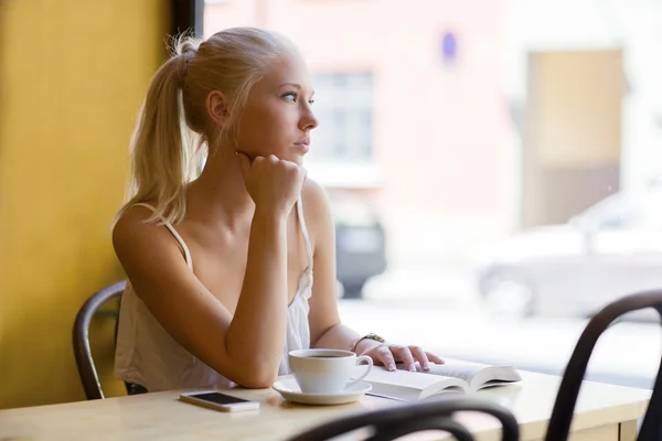 Nachdenkliche junge Frau im Café blickt aus dem Fenster — Stockfoto