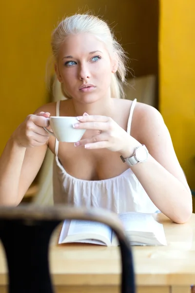 Unga blonda kvinnan dricker kaffe på café — Stockfoto