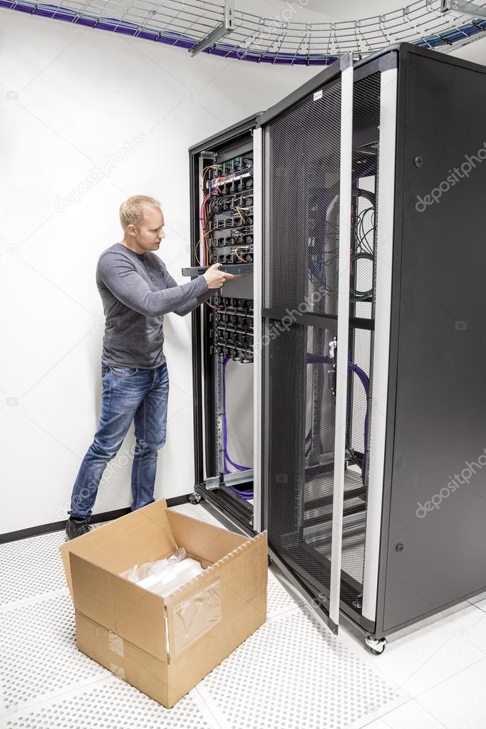 IT engineer installs network switch in datacenter