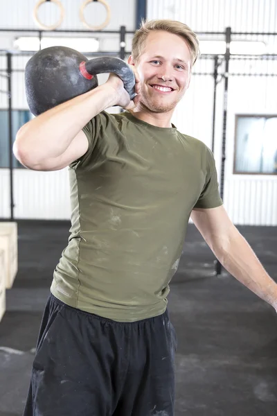 Lächelnder Mann mit Kettlebell im Fitnessstudio — Stockfoto