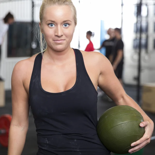 Sorridente giovane donna con palla slam al centro palestra — Foto Stock