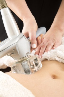 Woman receiving vacuum treatment at body clinic clipart