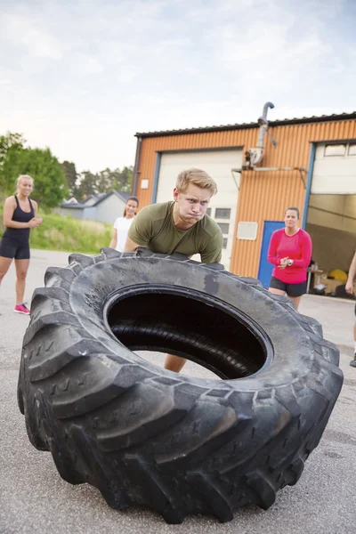 Hombre fuerte voltea neumático pesado al aire libre como entrenamiento — Foto de Stock