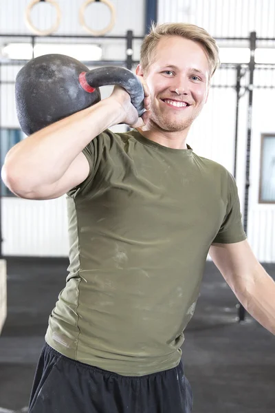 Uśmiechnięty mężczyzna z kettlebell w siłowni fitness — Zdjęcie stockowe