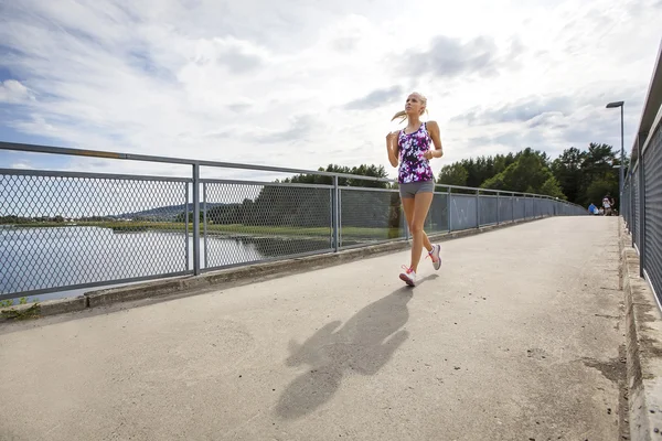 在桥上运行女人慢跑在户外的阳光下 — 图库照片