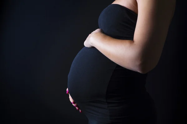 Femme enceinte se tient avec ses mains au ventre — Photo