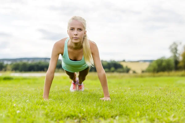 Ung kvinna gör armhävningar i parken — Stockfoto