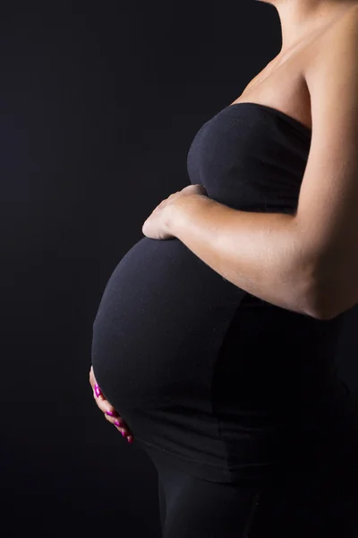 Беременная женщина стоит с руками у живота — стоковое фото