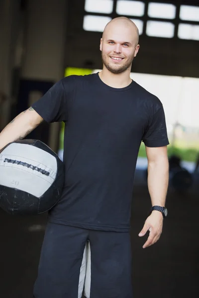 Χαμογελαστός νεαρός με το med-μπάλα στο γυμναστήριο γυμναστήριο — Φωτογραφία Αρχείου