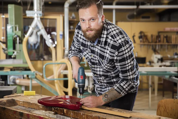 Hombre trabajando en taller con guitarra — Foto de Stock