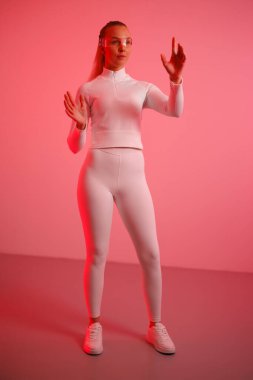 Akıllı gözlük takan ve kırmızı arka planda hareket eden genç bir kadın.