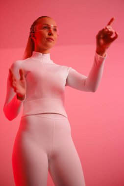 Akıllı gözlük takan ve kırmızı ışıklı arka plana el sallayan genç bir kadın.