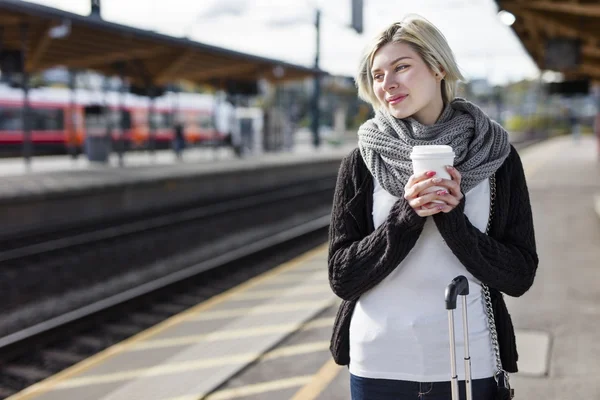 Kobieta pije kawę a ona czeka na pociąg — Zdjęcie stockowe